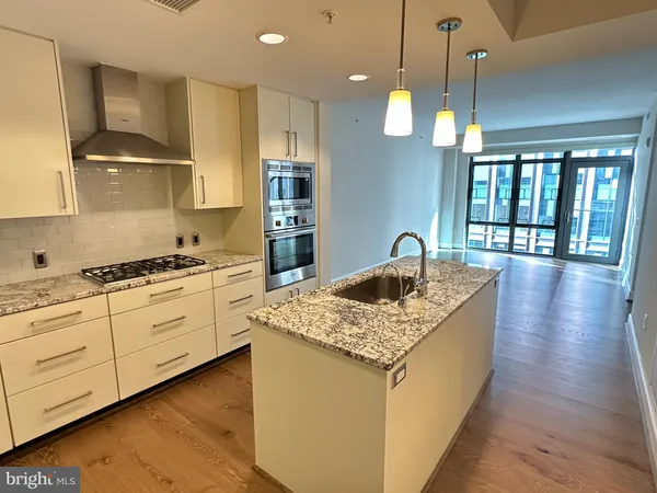 a kitchen with granite countertop a sink a counter top space and stainless steel appliances
