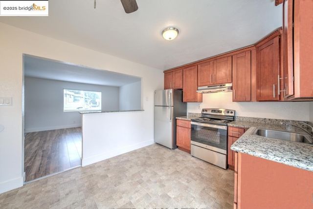 a kitchen with granite countertop a refrigerator stove top oven and sink
