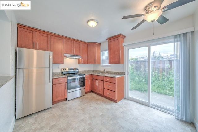 a kitchen with stainless steel appliances granite countertop a refrigerator a sink a stove a microwave and island with wooden cabinets