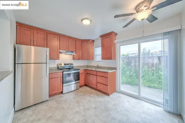 a kitchen with stainless steel appliances granite countertop a refrigerator a sink a stove a microwave and island with wooden cabinets