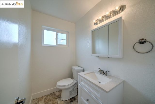 a bathroom with a toilet sink vanity granite and mirror