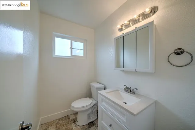 a bathroom with a toilet sink vanity granite and mirror