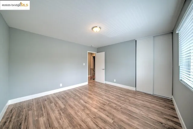 a view of an empty room with wooden floor and windows