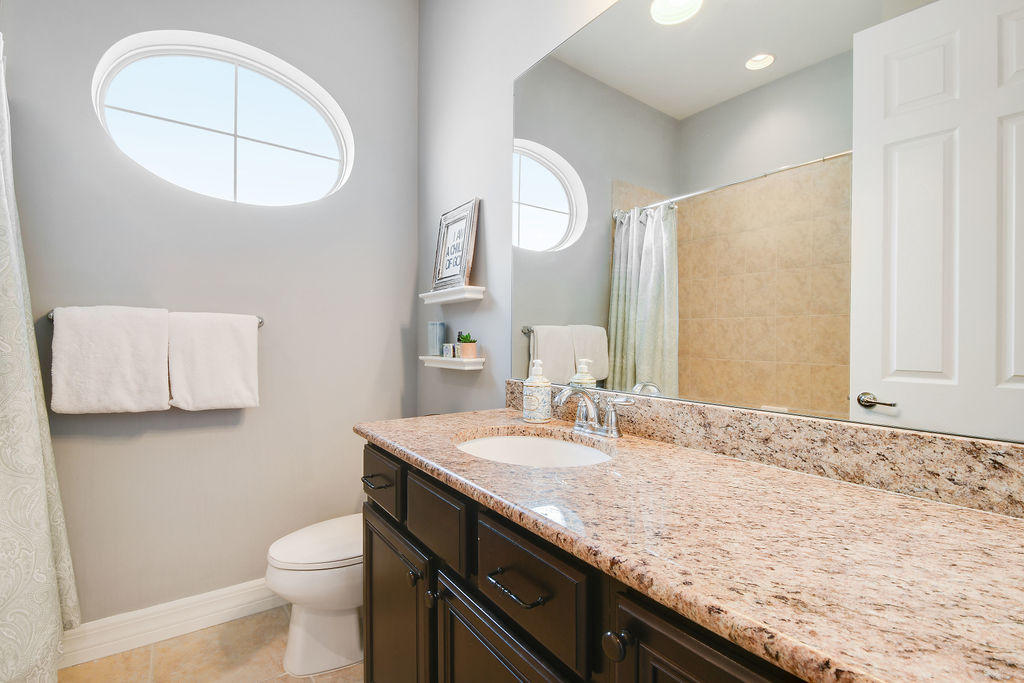 2719 Wymberly Drive Jupiter, FL 33458 - Photo 31 of 49 a bathroom with a granite countertop sink a toilet and a mirror
