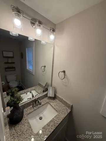a bathroom with a granite countertop sink a toilet and shower