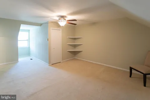 an empty room with a chandelier fan and windows