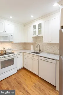 a kitchen with granite countertop white cabinets and white appliances