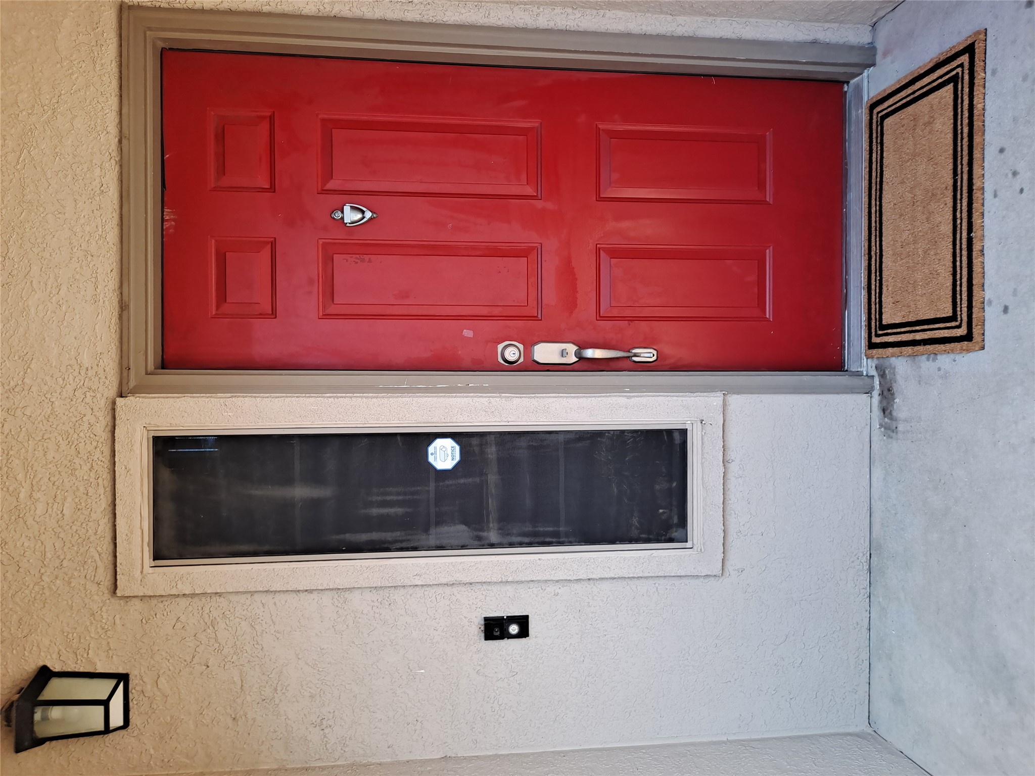 11203 Ranch Road 2222, Unit 2404 Austin, TX 78732 - Photo 2 of 28 Red paneled entry door with polished hardware, featuring a coordinating sidelight and an exterior wall lantern