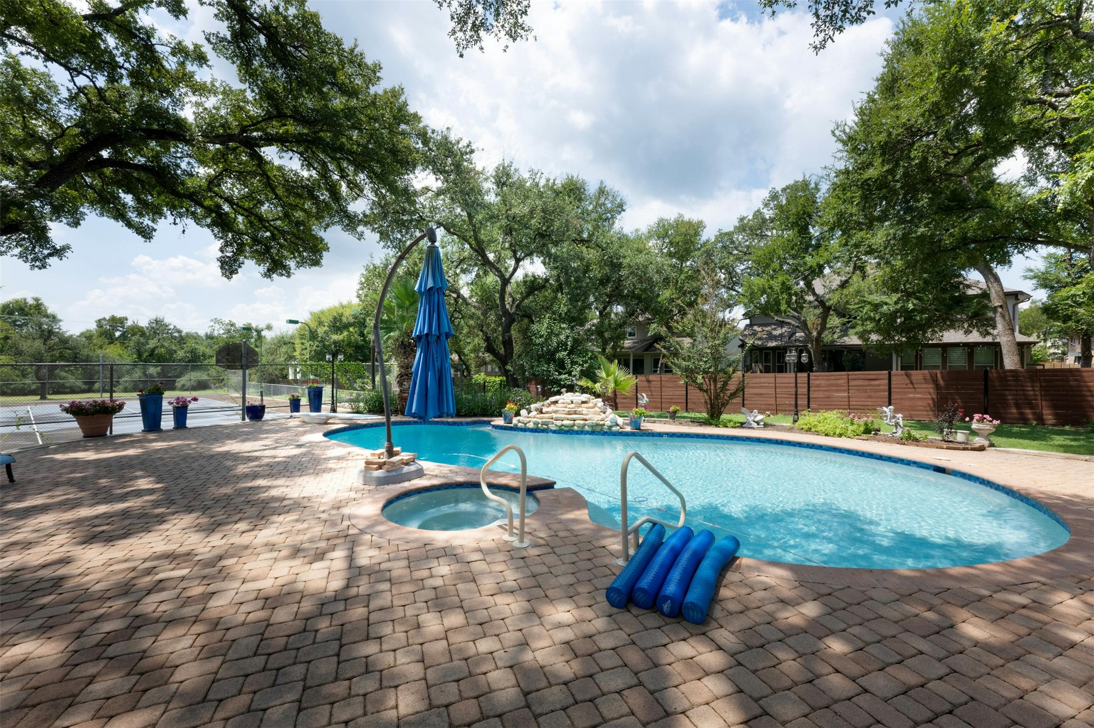 9911 Anderson Mill Road Austin, TX 78750 - Photo 25 of 29 An inviting backyard oasis awaits with a sparkling pool and spa, set on a paver patio amidst mature trees.