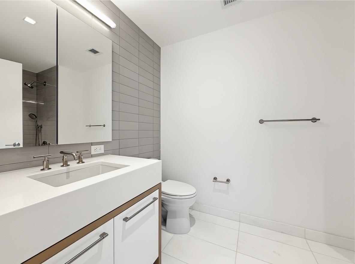 75 Park Lane South, Unit 3202 Jersey City, NJ 07310 - Photo 8 of 40 a bathroom with a sink a toilet and a mirror