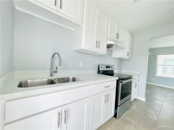 a kitchen with granite countertop white cabinets and stainless steel appliances
