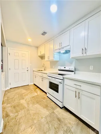 a view of a livingroom with a chandelier fan and refrigerator in kitchen