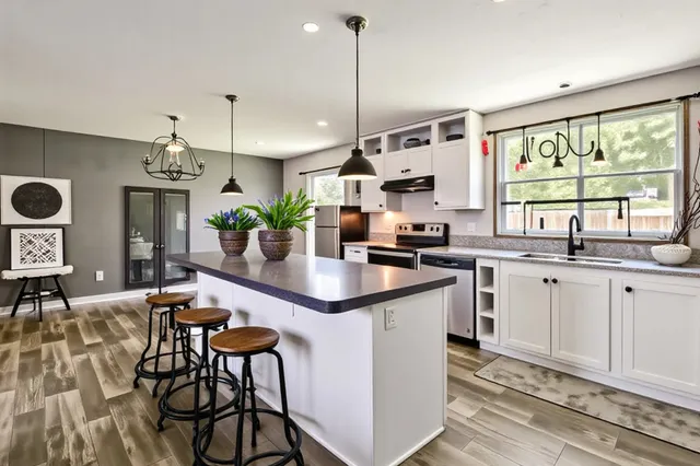 a kitchen with stainless steel appliances granite countertop a sink a stove a refrigerator and cabinets
