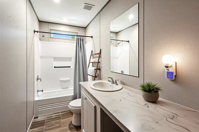 a bathroom with a granite countertop sink a toilet and shower