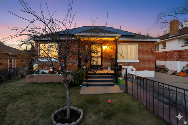 View of front of property featuring roof mounted solar panels, brick siding, and a patio area
