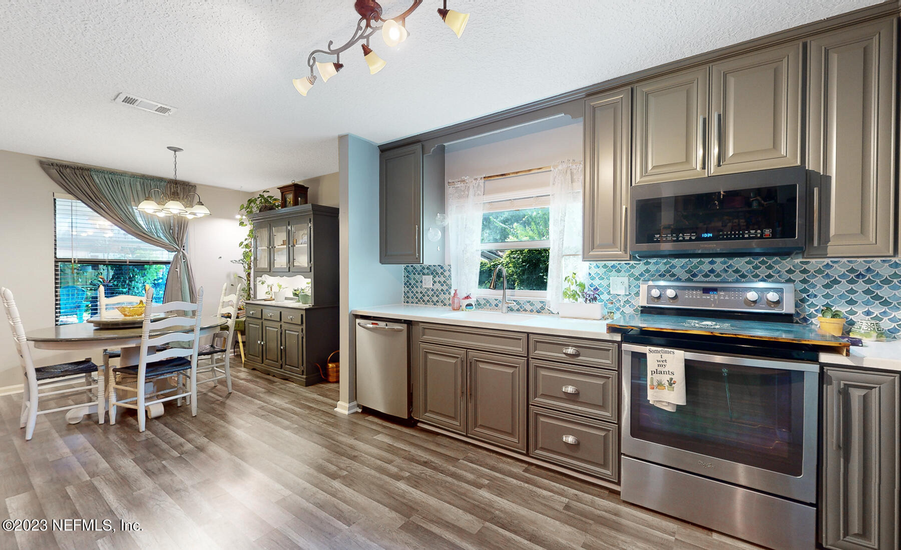 11338 Rustic Pines Circle East Jacksonville, FL 32257 - Photo 14 of 33 a kitchen with stainless steel appliances granite countertop wooden floors a stove a microwave a window and white cabinets