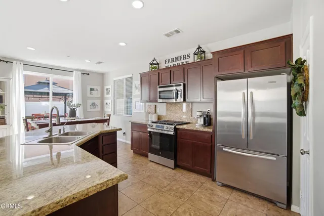 a kitchen with stainless steel appliances granite countertop a refrigerator a stove and a sink