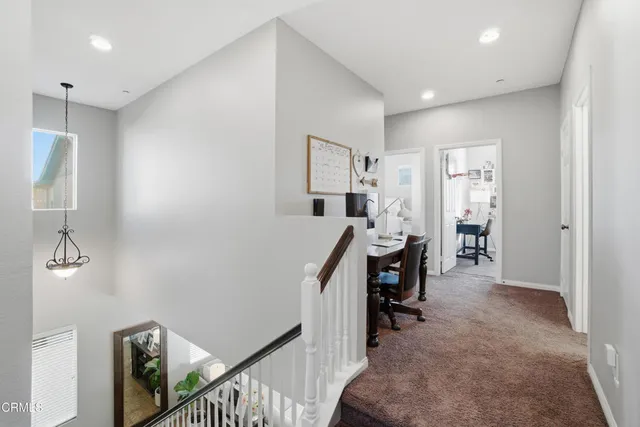 a view of a hallway to a livingroom with furniture and windows