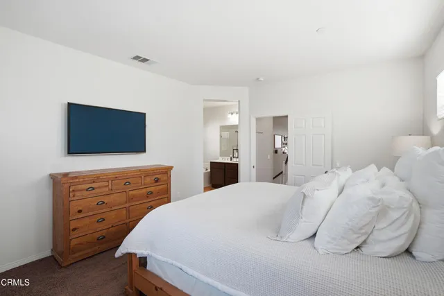 a bedroom with a bed and a flat tv screen on dresser