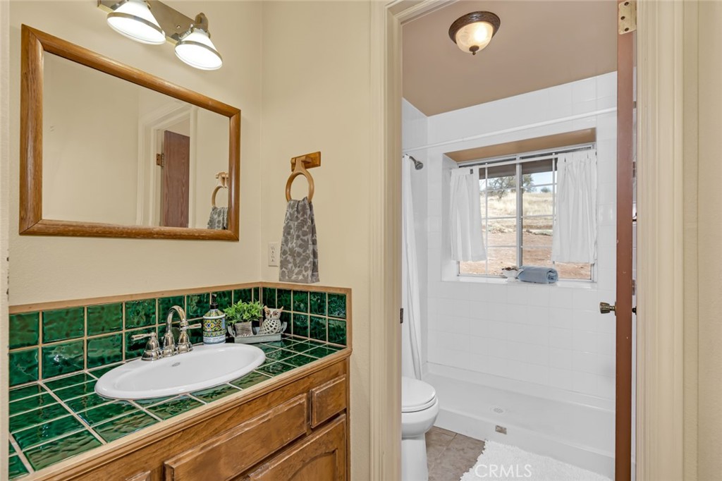 5030 Creek Front Road Catheys Valley, CA 95306 - Photo 29 of 69 a bathroom with a granite countertop sink mirror vanity and toilet