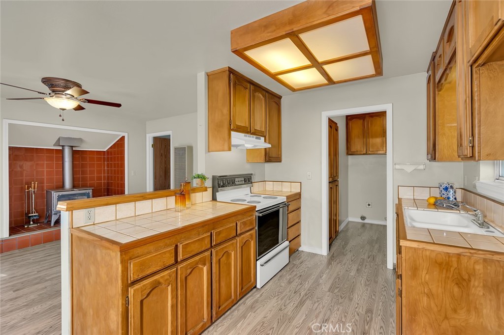 5030 Creek Front Road Catheys Valley, CA 95306 - Photo 50 of 69 a kitchen with a stove a sink dishwasher and a refrigerator with wooden floor