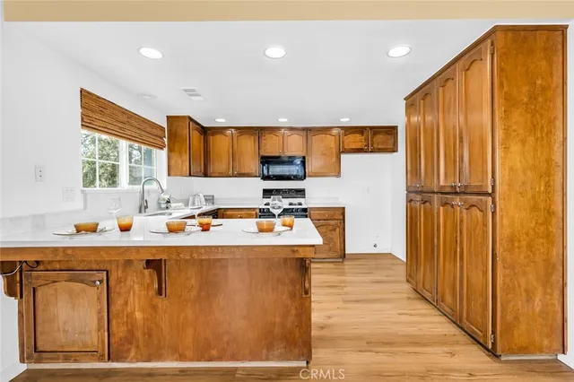 a kitchen with stainless steel appliances granite countertop a refrigerator a sink dishwasher a stove with wooden cabinets and a large window