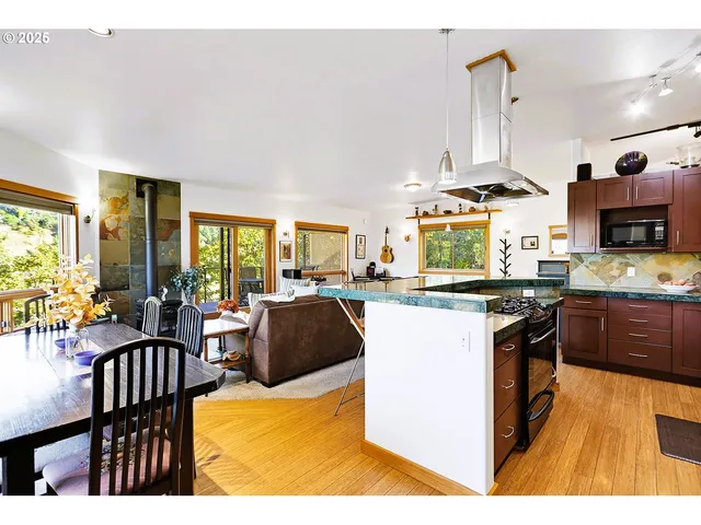 a kitchen with stainless steel appliances kitchen island granite countertop a stove a sink dishwasher and white cabinets with wooden floor