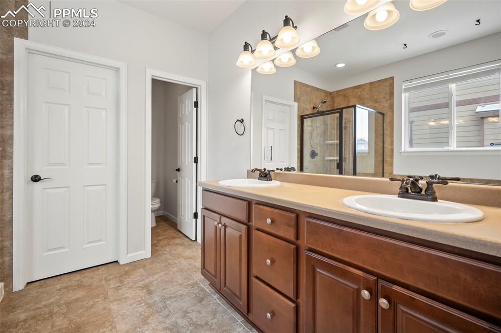 8238 Hollygrape Lane Colorado Springs, CO 80927 - Photo 13 of 35 a spacious bathroom with double vanity sinks a vanity two mirror and a shower