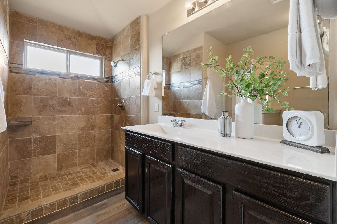 1432 Blake Street Leander, TX 78641 - Photo 17 of 26 a bathroom with a granite countertop sink a mirror and shower