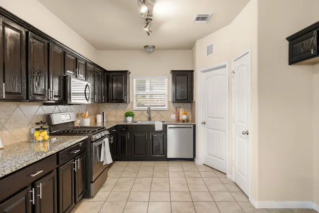a kitchen with stainless steel appliances granite countertop a stove sink microwave and refrigerator
