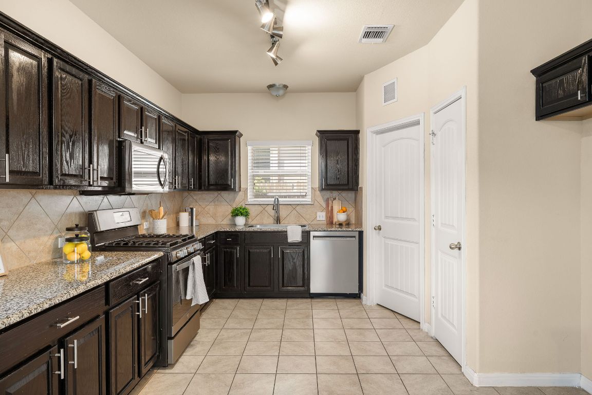 1432 Blake Street Leander, TX 78641 - Photo 7 of 26 a kitchen with stainless steel appliances granite countertop a stove sink microwave and refrigerator