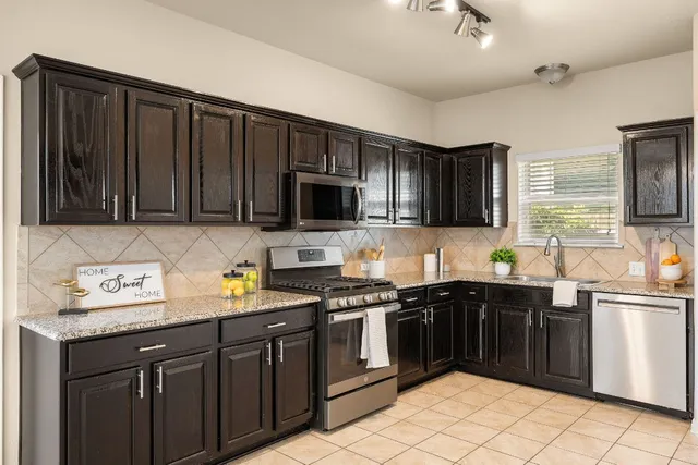 a kitchen with stainless steel appliances granite countertop a sink stove microwave and cabinets