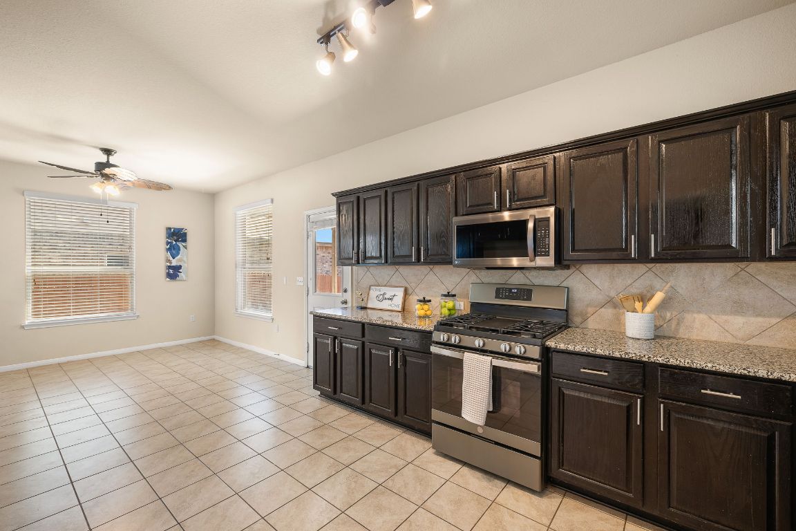 1432 Blake Street Leander, TX 78641 - Photo 10 of 26 a kitchen with stainless steel appliances granite countertop a stove top oven a sink dishwasher and a microwave oven on the blue kitchen countertops