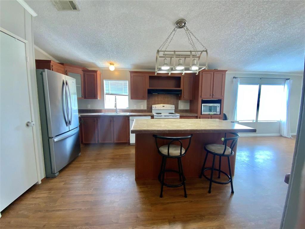11255 Sam Reynolds Road Justin, TX 76247 - Photo 7 of 19 a kitchen with kitchen island granite countertop a sink cabinets and stainless steel appliances