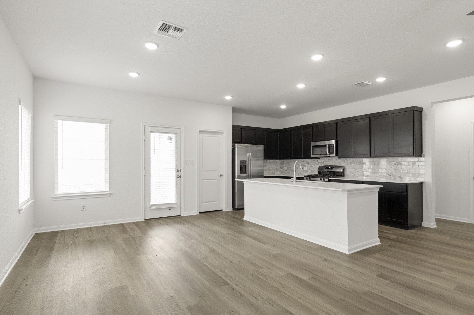 3725 Pin Oak Hills Seguin, TX 78155 - Photo 7 of 21 Kitchen featuring dark cabinets, an island with sink, appliances with stainless steel finishes, recessed lighting, and decorative backsplash
