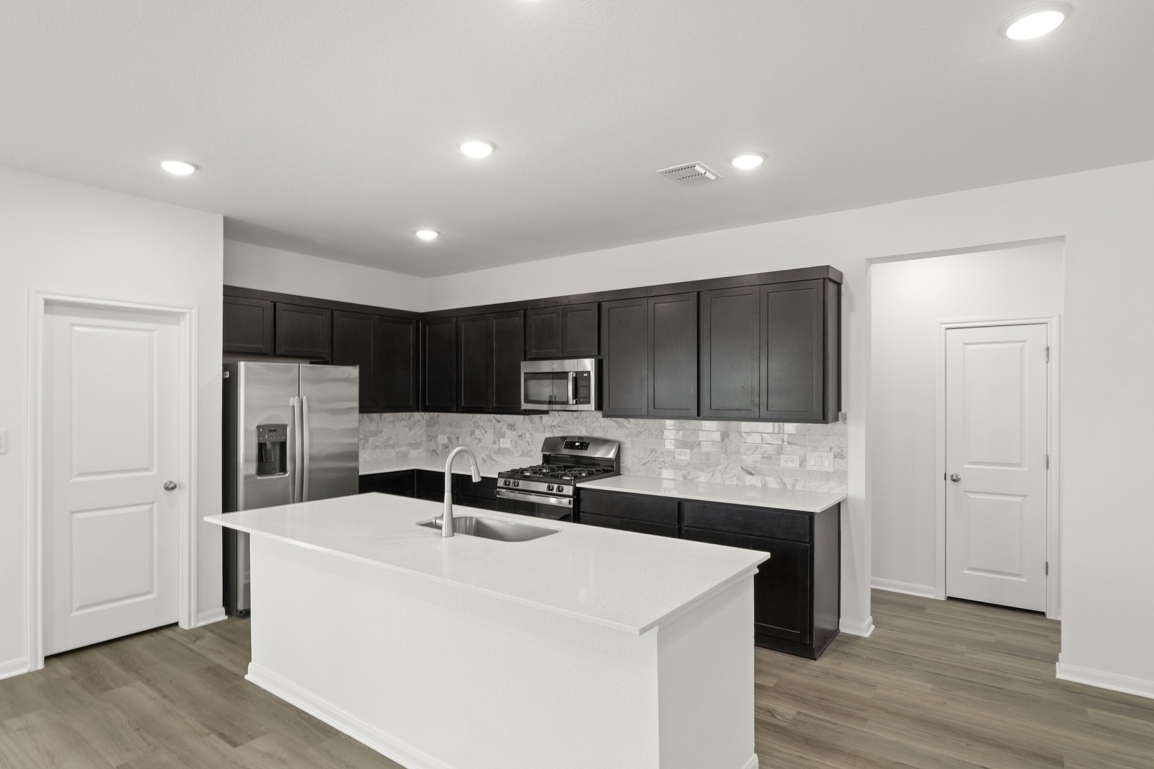 3725 Pin Oak Hills Seguin, TX 78155 - Photo 8 of 21 Kitchen featuring stainless steel appliances, light wood-style flooring, an island with sink, light stone countertops, and tasteful backsplash