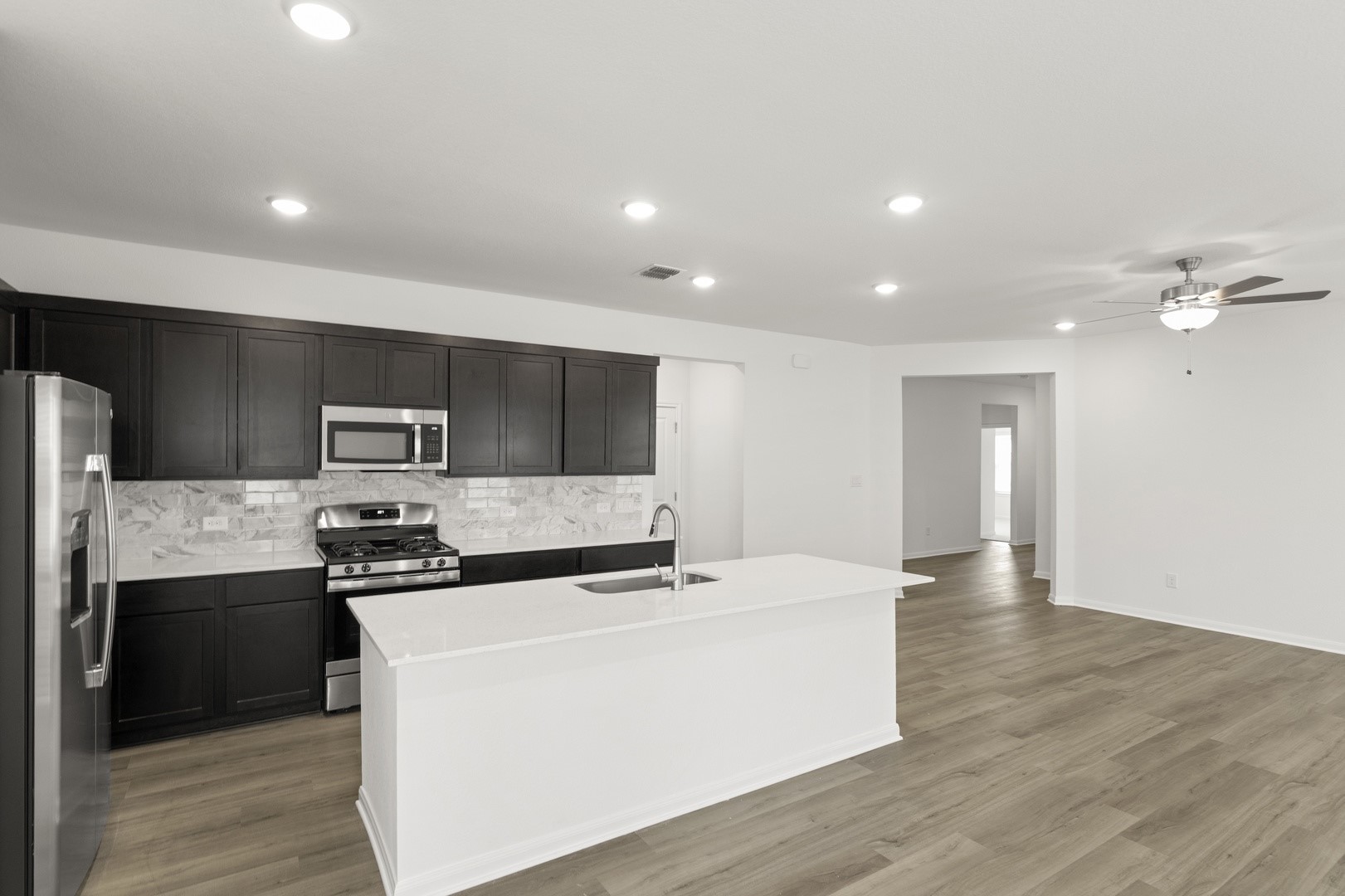 3725 Pin Oak Hills Seguin, TX 78155 - Photo 9 of 21 Kitchen featuring appliances with stainless steel finishes, light wood-type flooring, recessed lighting, decorative backsplash, and a center island with sink