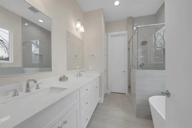 a spacious bathroom with a double vanity sink mirror and shower