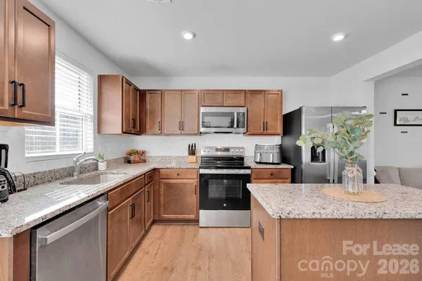 a kitchen with kitchen island granite countertop a sink a counter top space appliances and cabinets