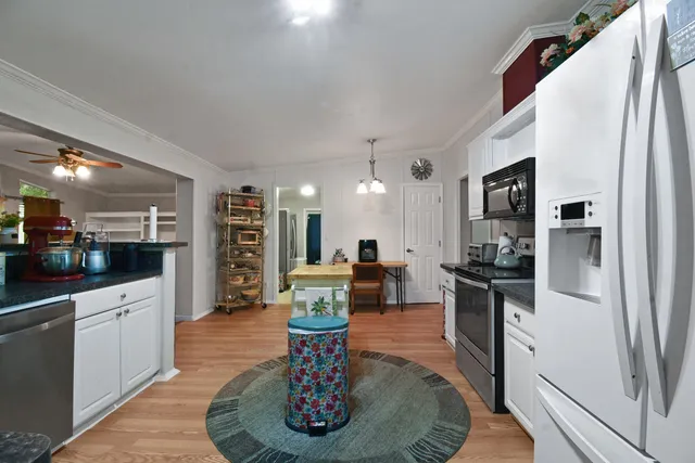 a living room with stainless steel appliances furniture a rug kitchen view and a chandelier