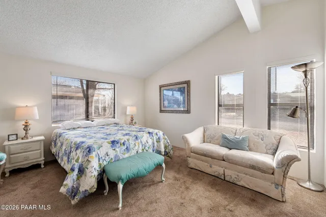 a spacious bedroom with a bed a couch and a large window