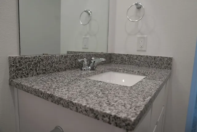 a bathroom with a granite countertop sink and a mirror