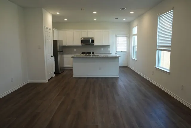 a view of kitchen with granite countertop stainless steel appliances counter space and wooden floor
