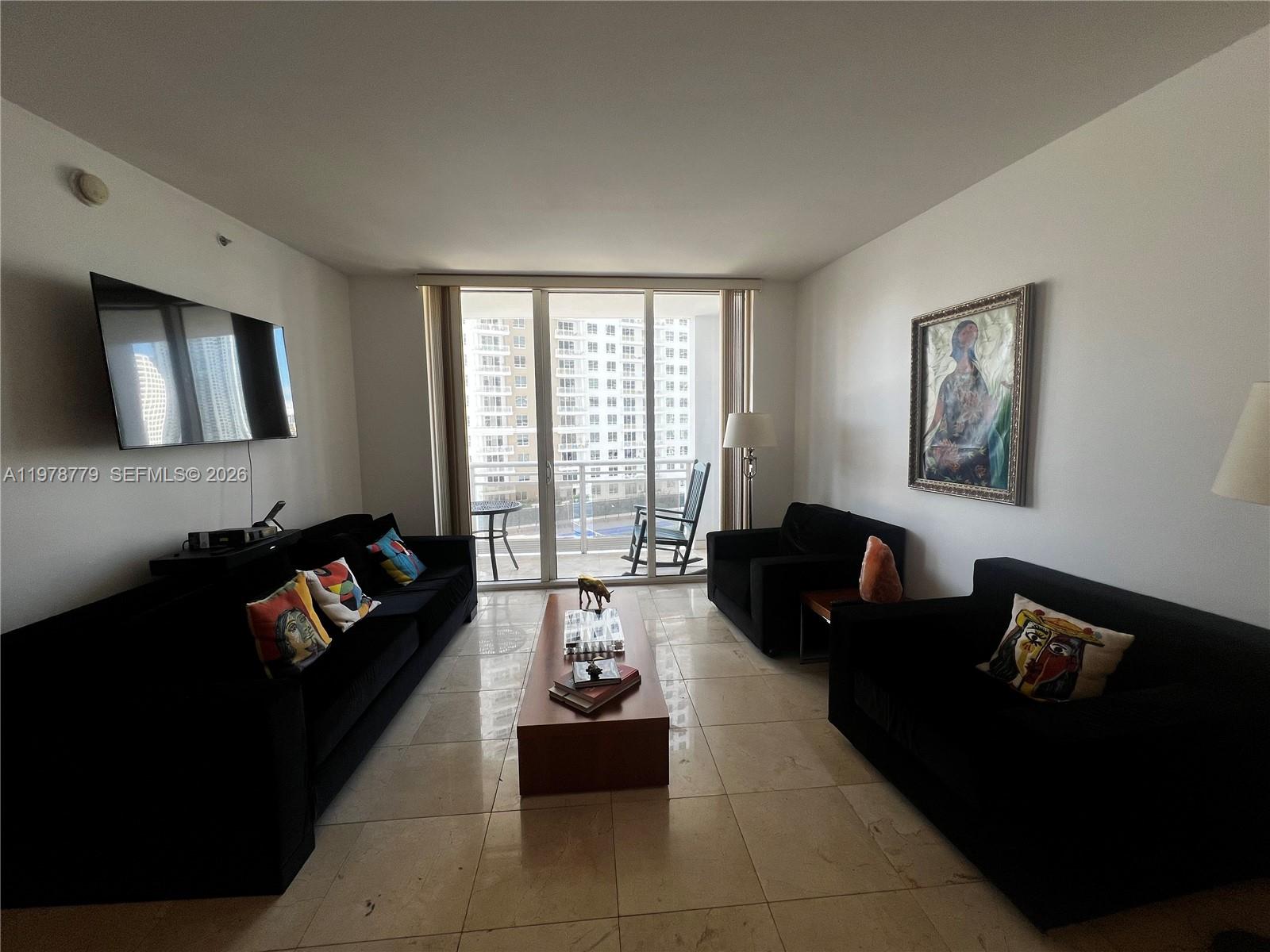 901 Brickell Key Boulevard, Unit 1001 Miami, FL 33131 - Photo 5 of 18 a living room with furniture and a flat screen tv
