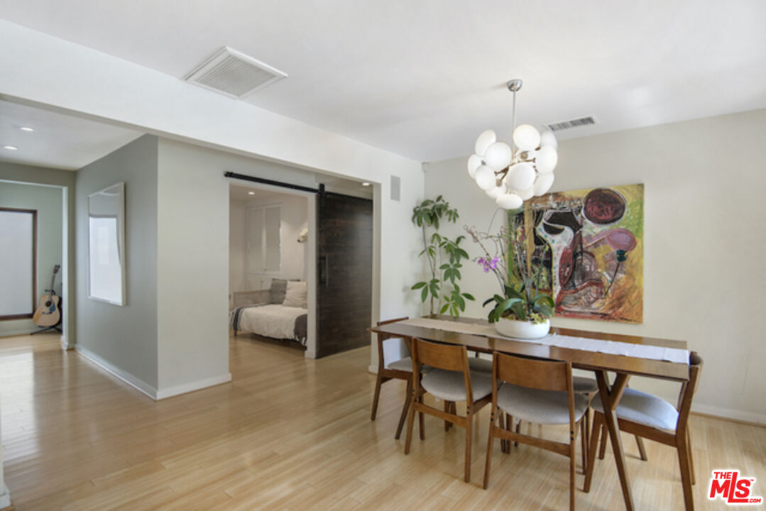 8152 Amor Road Los Angeles, CA 90046 - Photo 10 of 27 a dining room with wooden floor a chandelier a wooden table and chairs