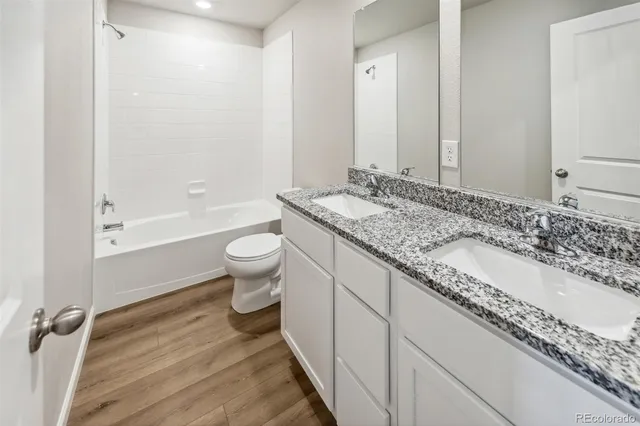 a bathroom with a granite countertop sink a toilet and shower