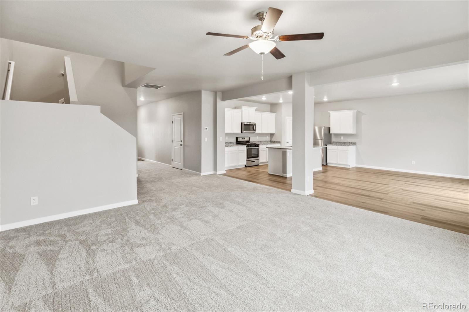 2175 Alyssa Street Fort Lupton, CO 80621 - Photo 6 of 39 a view of a livingroom with a ceiling fan a kitchen space with a sink and a ceiling fan