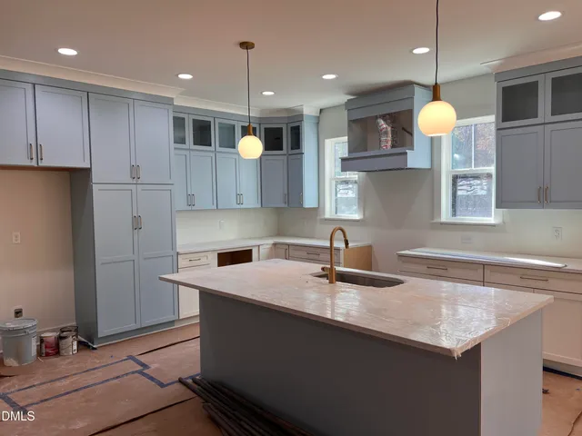 a kitchen with kitchen island granite countertop a sink a counter top space cabinets and stainless steel appliances