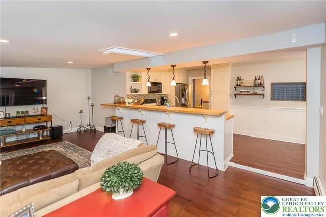 a living room with stainless steel appliances furniture wooden floor and kitchen view