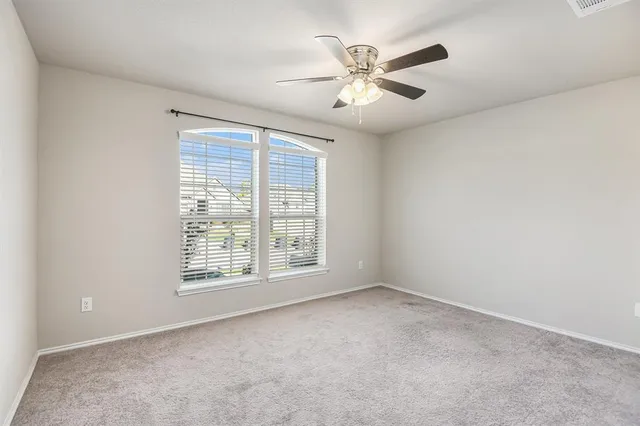 an empty room with chandelier fan and windows